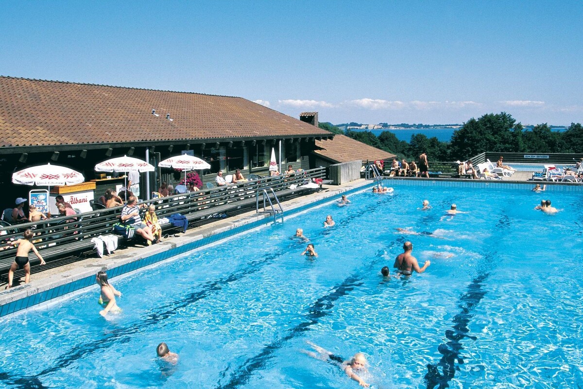 A swimming pool with multiple lanes, spectators, and umbrellas.