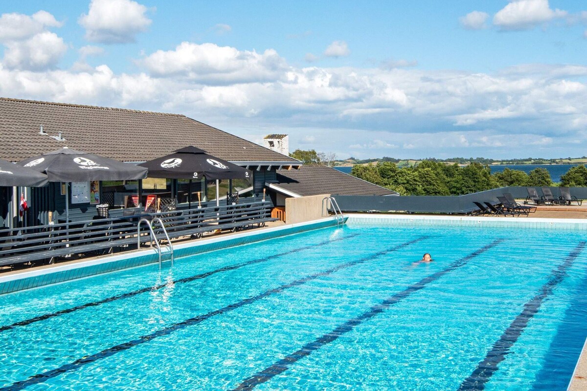 A swimming pool with clear blue water, a lifeguard stand, and lounge chairs.