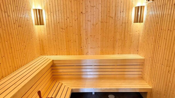 Un sauna avec des bancs en bois et un seau.