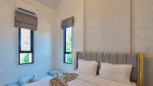 A modern bedroom with a large bed, two windows with curtains, an air conditioning unit, and a wall with vertical lines. - Pool&Play - Modern Private Pool Villa in Pattaya (Muang Pattaya)