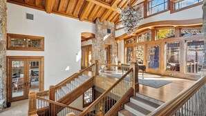 A spacious interior with a wooden staircase, stone walls, and large windows. - Lucky Boot Lodge - Incredible Views, Walk to Ski (Edwards)