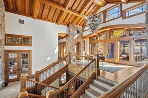 Ein geräumiger Innenraum mit einer Holztreppe, Steinwänden und großen Fenstern.
