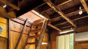 A rustic wooden cabin interior with a wooden staircase, a bed with a white mattress, and a window with a curtain. - Senbo Eco Resort Cox's Bazar (Cox's Bazar)
