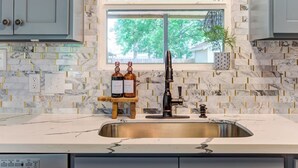 A kitchen with marble backsplash, a window, and a sink.