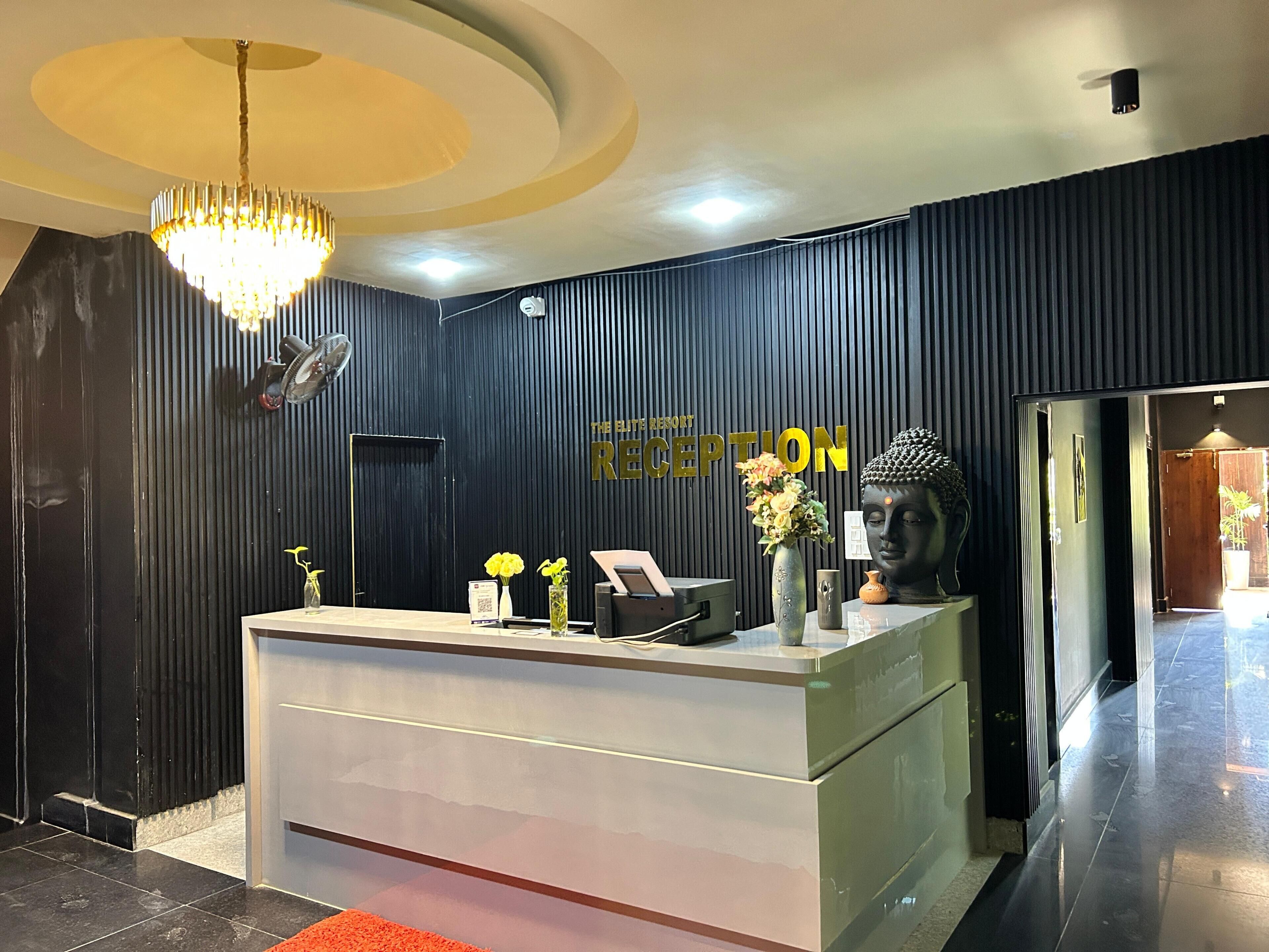 A reception desk with a modern design, a chandelier, and a Buddha statue.