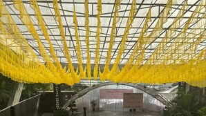 Ein Innenhofgarten mit Glasdach, grünem Kunstrasen und Tischen mit Stühlen, die zum Essen bereitstehen.