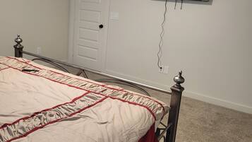 A bedroom with a bed, a television mounted on the wall, and a door.