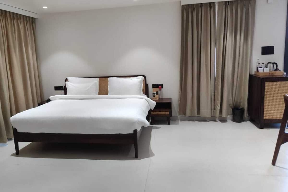 A hotel room with a large bed, a nightstand, a dresser, and a chair.