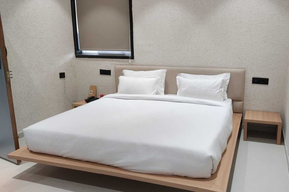 A modern bed with a wooden frame, two bedside tables, and a window above the bed.