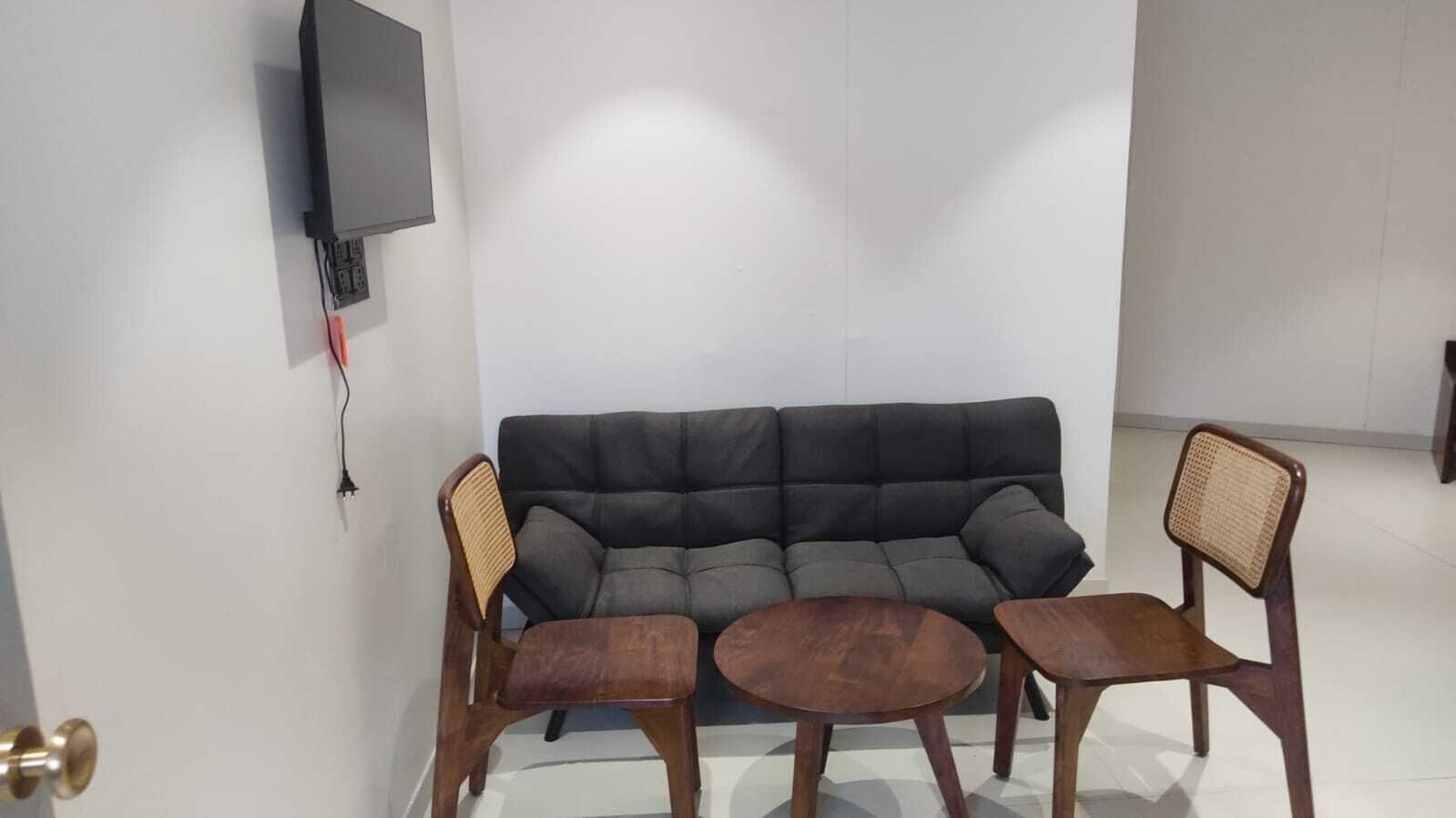 Een woonkamer met een bank, twee houten stoelen en een kleine tafel.