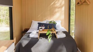 A modern bedroom with a bed, bedside table, and a window.