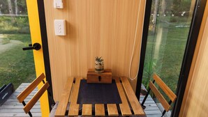 A wooden table with a black mat, two wooden chairs, a small wooden box with a plant, and a door with a light switch.