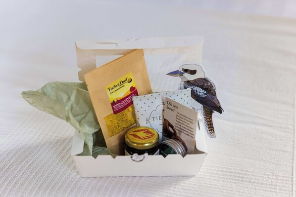 Una caja de regalo con una pegatina de pájaro, un frasco y una tarjeta.