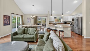 A spacious living room with a green sofa, a dining area with a table and chairs, and a kitchen with stainless steel appliances. - Mountain retreat w/deck, game room & dog-friendly (Hedgesville)