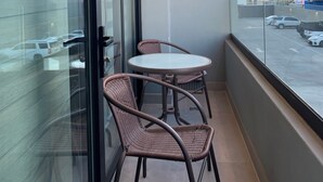 A balcony with a glass door, two wicker chairs, and a small round table. - Alameda Apartment (Tijuana)