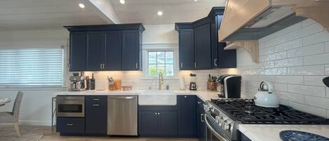 Una cocina moderna con armarios oscuros, electrodomésticos de acero inoxidable y suelo de madera.