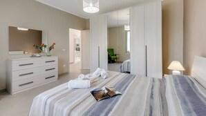 Une chambre d’hôtel avec un lit, une commode, un miroir et une lampe.