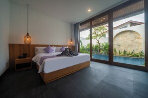 Un dormitorio moderno con una cama grande, una mesita de noche, una lámpara colgante y vistas a una piscina a través de amplios ventanales.