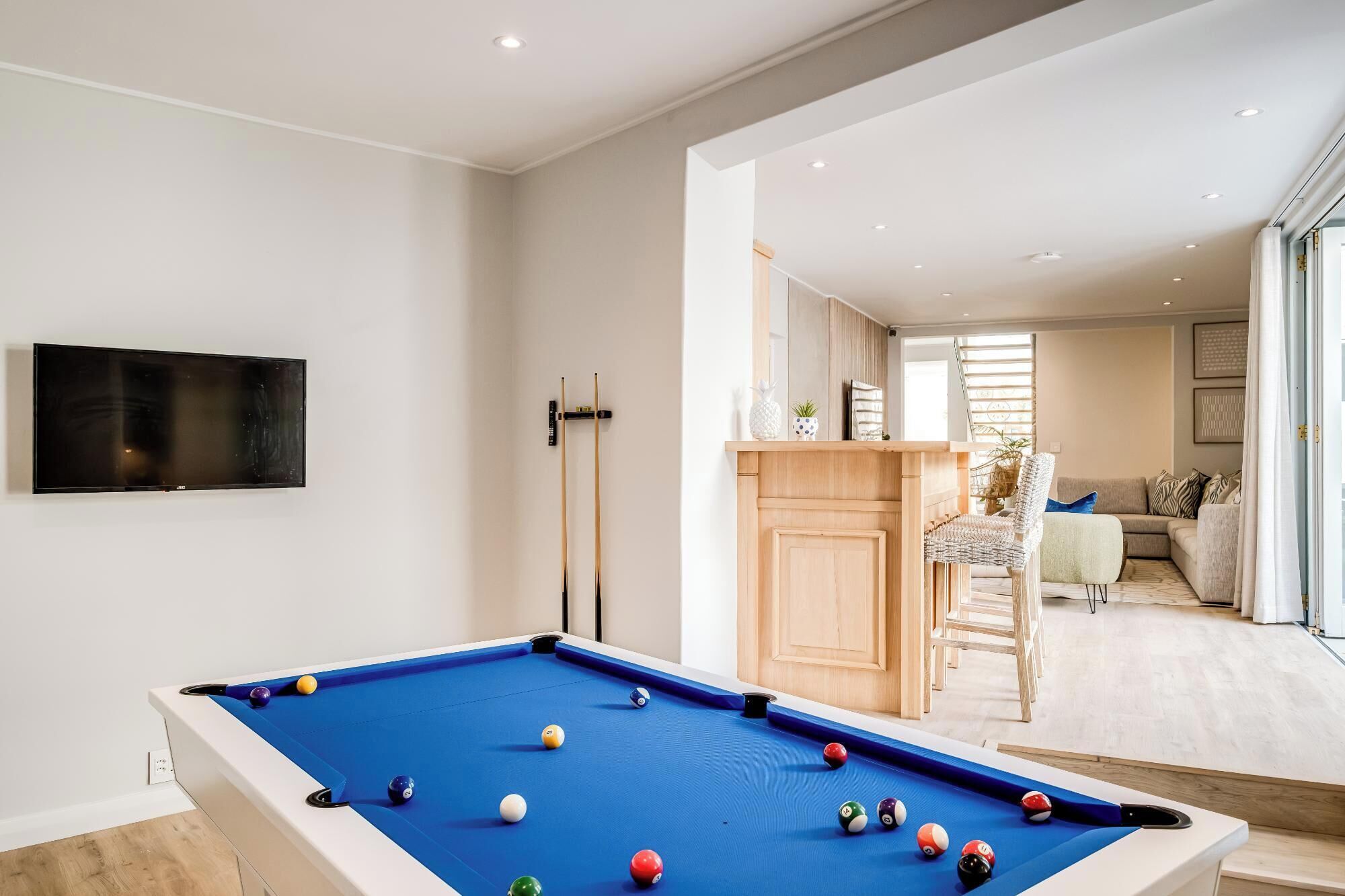 A pool table with balls, a television mounted on the wall, and a seating area with a sofa and chairs.