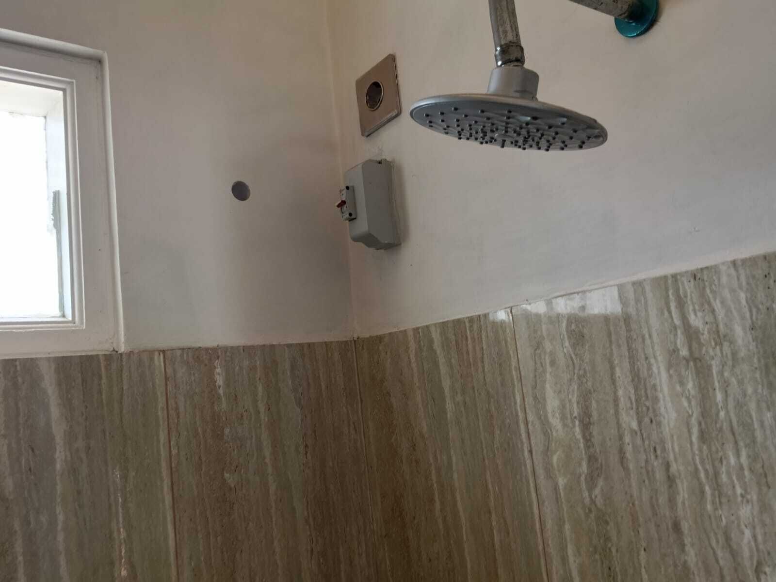A showerhead mounted on a wall with a control box below it.