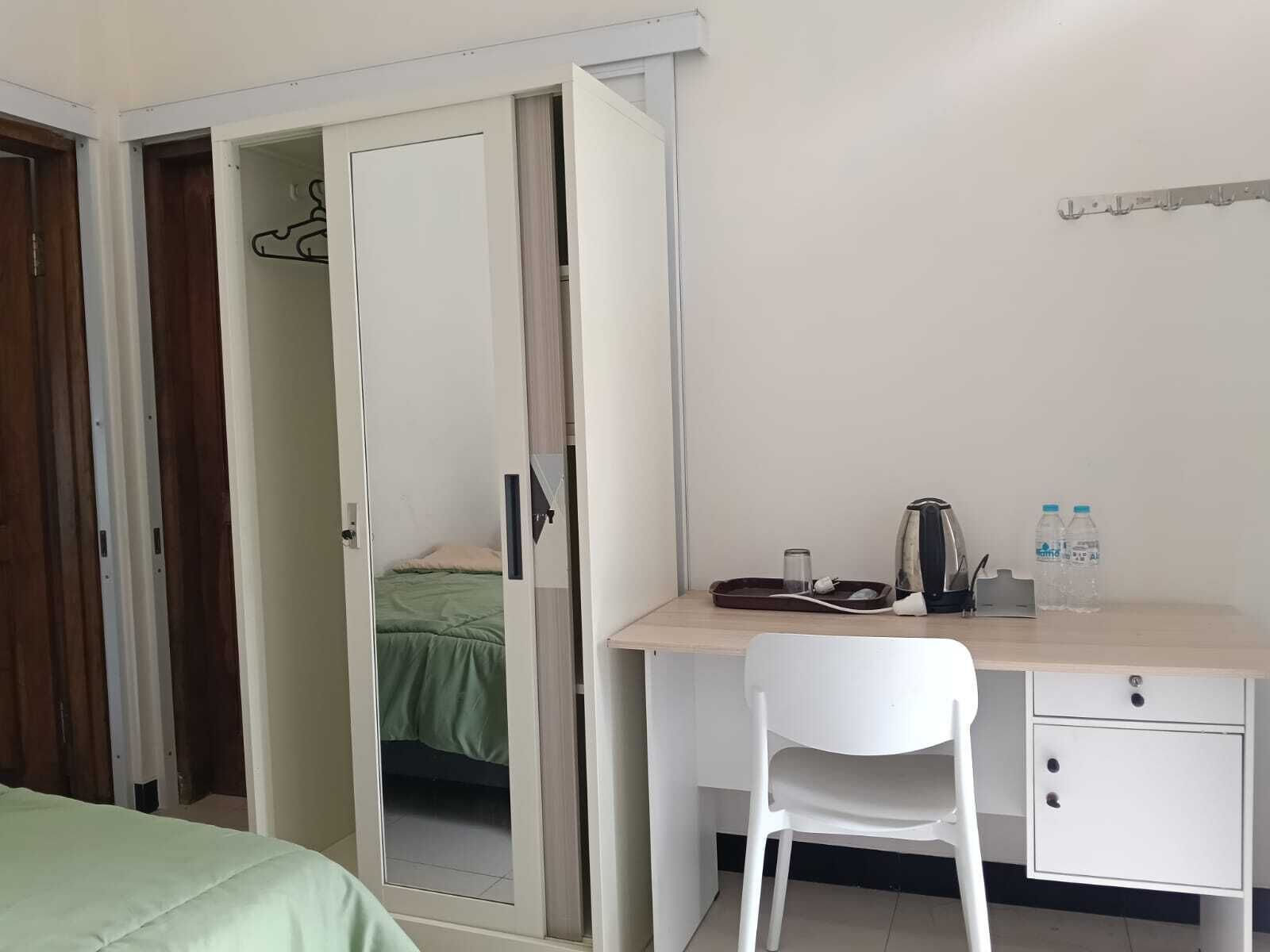 Quarto com cama, escrivaninha, cadeira, armário e pequena cozinha.