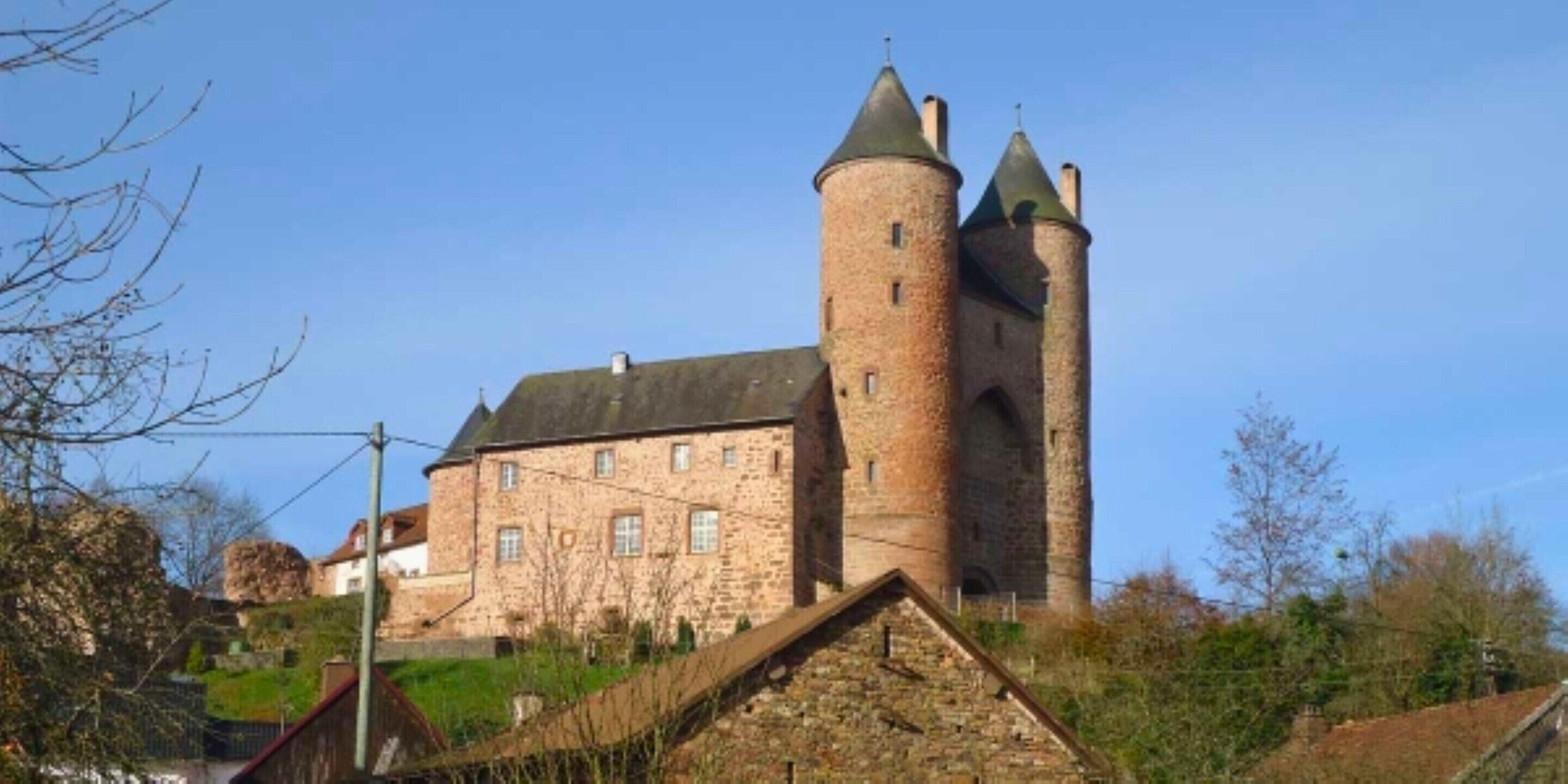 A historic stone building with a prominent tower and a smaller building attached to it.