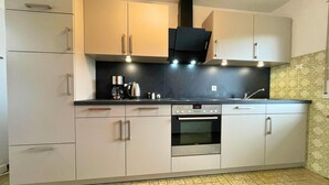 A modern kitchen with light-colored cabinets, a black countertop, and a stainless steel oven. - Holiday Home in Birresborn With Balcony (Birresborn)