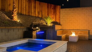 Una piscina con cubierta de madera, un muro de ladrillo y una chimenea decorativa.