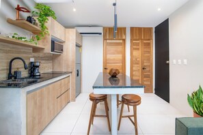 Una cucina moderna con mobili in legno, un piano di lavoro nero, una macchina da caffè e due sgabelli.