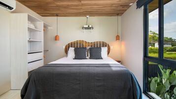 A bedroom with a bed, a wardrobe, a ceiling fan, and a view of greenery outside.
