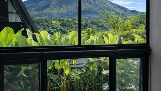 Habitació moderna amb grans finestres, una banyera d'hidromassatge i vista a una muntanya.