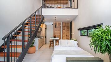 A compact, modern interior with a staircase, a kitchen area, a dining table, and a bed.