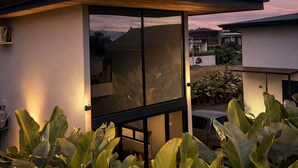 Una casa moderna amb una porta de vidre, envoltada de plantes verdes grans.