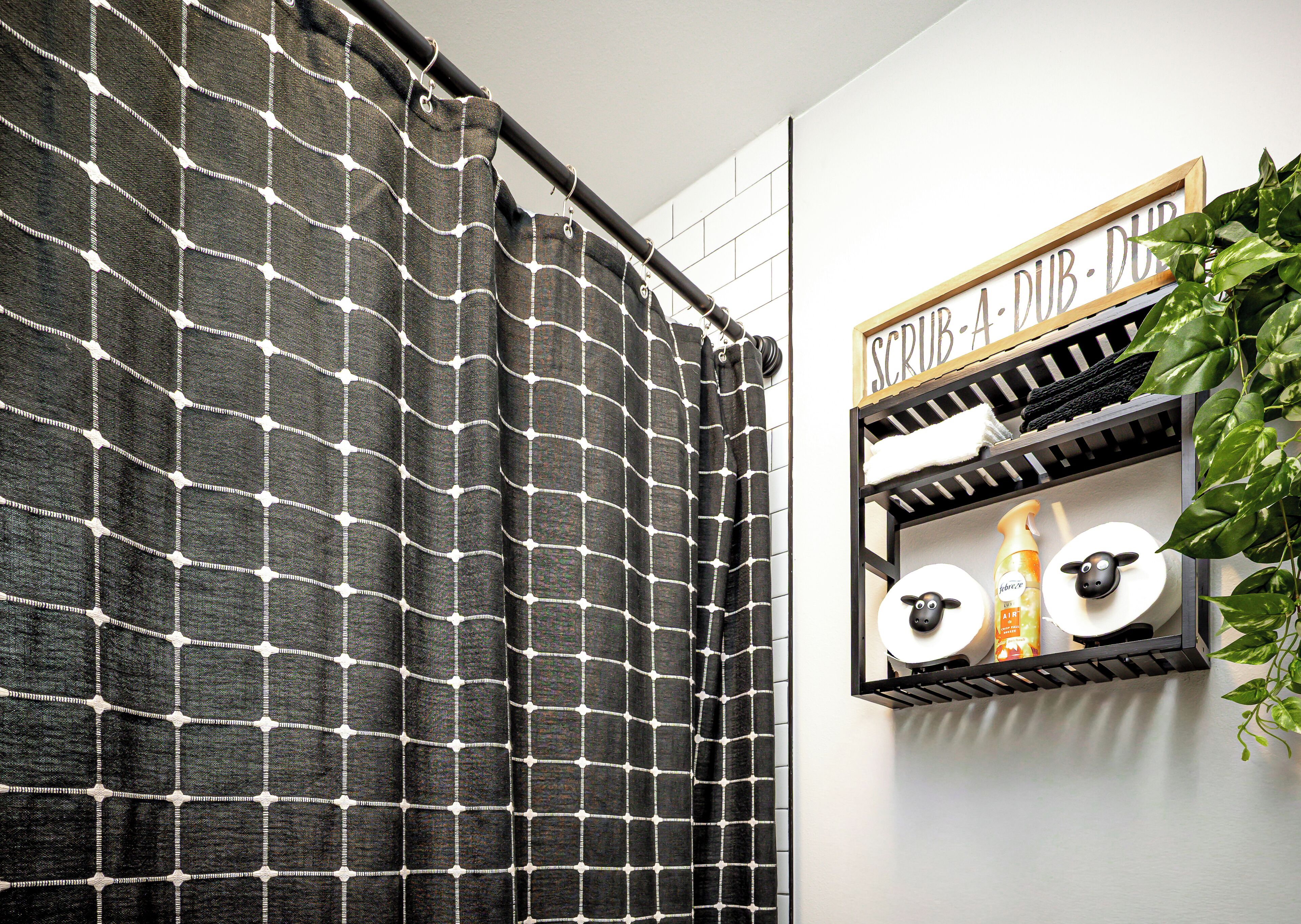 A bathroom with a black and white checkered shower curtain, a shelf with toiletries, and a sign that reads "SCRUB-DUB-DUB".