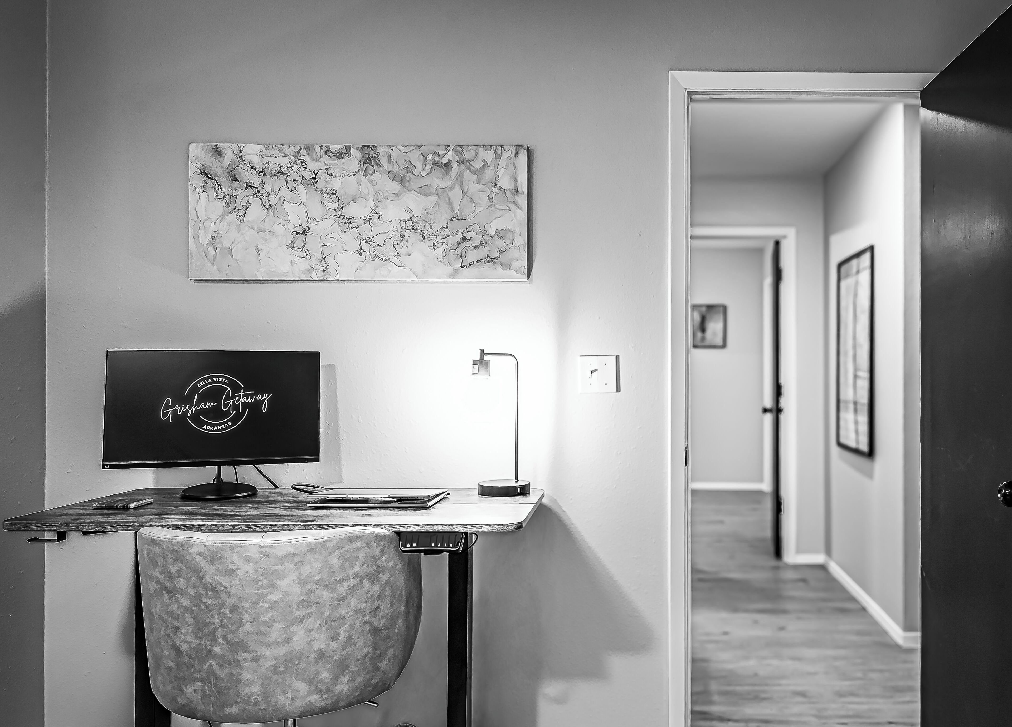 Een moderne kantoorruimte met een bureau, computer, stoel en een wandlamp.