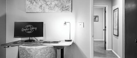 Een moderne kantoorruimte met een bureau, computer, stoel en een wandlamp.