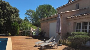 Une terrasse en bois avec des chaises longues et un espace aménagé au bord de la piscine.