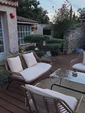 Eine Terrasse im Freien mit Korbmöbeln, einer Steinwand und einem Ziegeldach.
