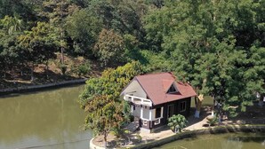 A small house with a red roof by a calm lake, surrounded by trees. - Venus Resort Bandarban (Bandarban)