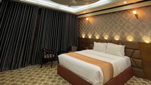 A hotel room with a bed, a ceiling fan, a nightstand, and a patterned carpet. - Venus Resort Bandarban (Bandarban)