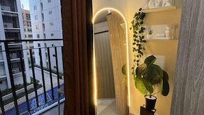 A balcony with a view of a cityscape, a wooden door, and a plant on the floor. - Cozy Haven (Pasay)