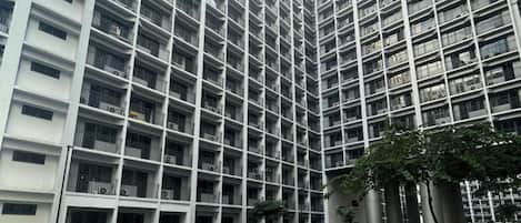Un edificio residencial alto con varios balcones y una piscina al frente.