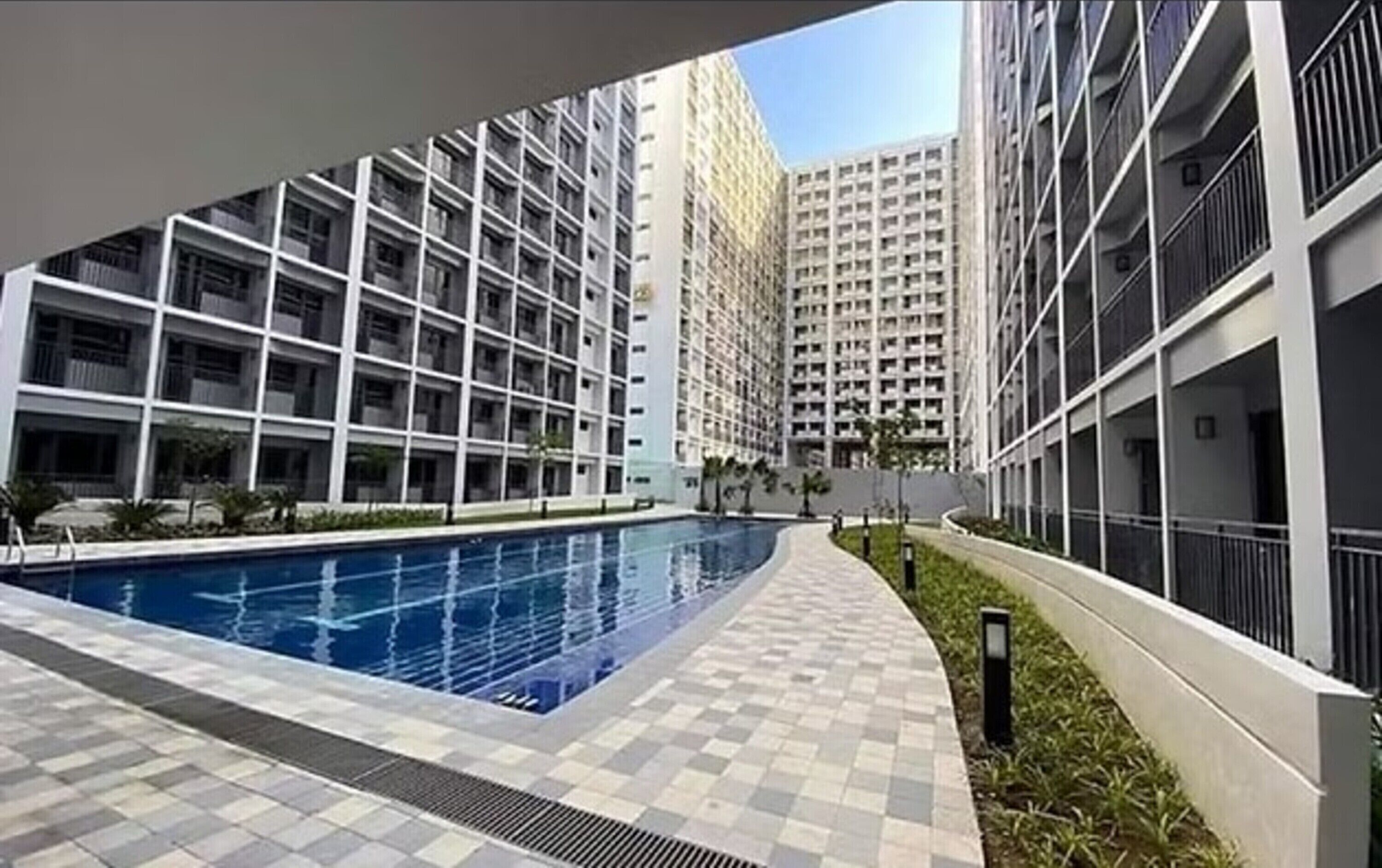 A modern residential building with a swimming pool, featuring a checkered tile pathway leading to the pool.
