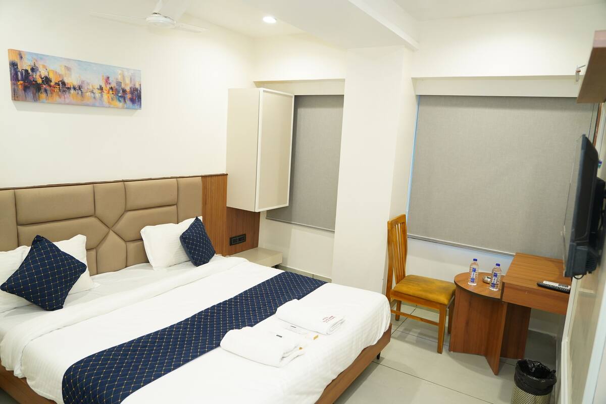 Une chambre d’hôtel avec un lit, un bureau, une chaise, une télévision et un tableau au mur.