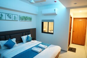 Une chambre d’hôtel avec un lit, des oreillers, une fenêtre, un appareil de climatisation et une porte.