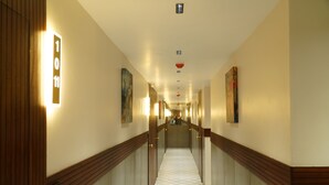 Een hotelgang met een receptiebalie, een incheckruimte en een trap naar de bovenverdiepingen.