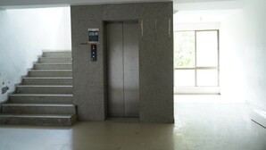 Een moderne lift in een gebouw, met een trap die ernaartoe leidt.