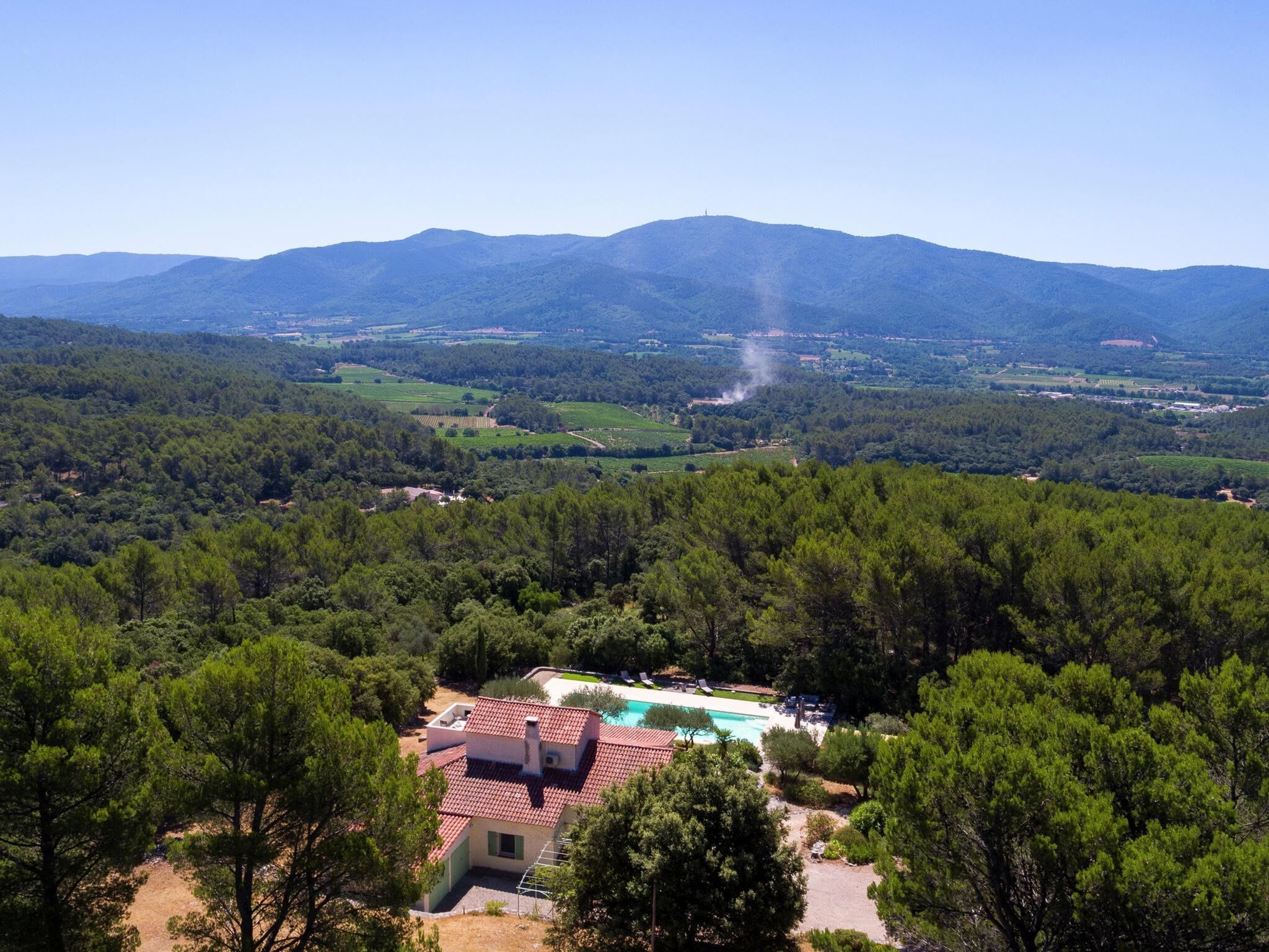 Une villa avec piscine, entourée d’une forêt dense et avec des montagnes en arrière-plan.
