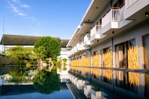 A modern hotel with a reflective pool, a tree, and a bamboo fence. - THE ULU Beach Club and Bungalows (Lembongan Island)