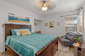 A bedroom with a bed, a ceiling fan, a window with blinds, a small table with a plant, and a painting on the wall. - Historic Quiet Home W/Free Parking by Hollywood (Burbank)